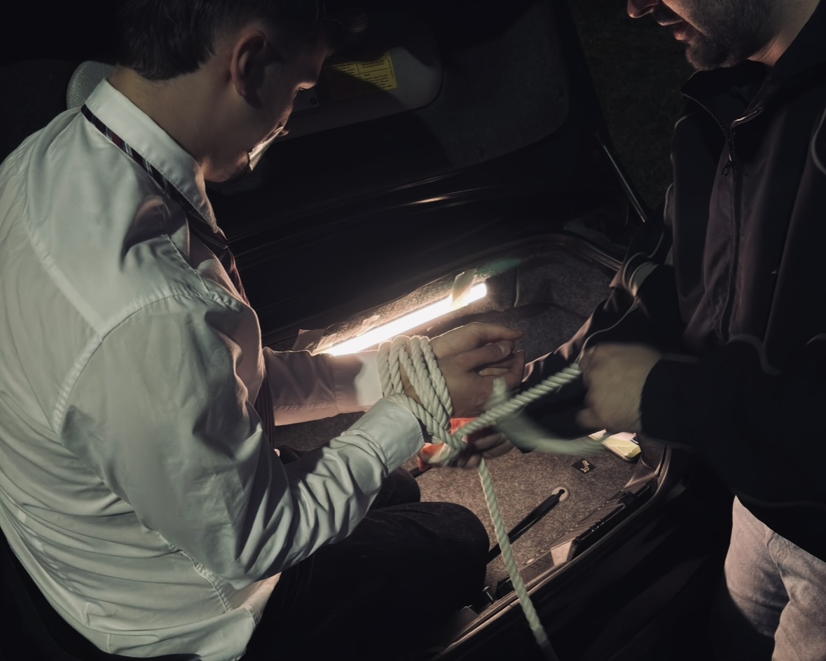 A behind-the-scenes film setup inside the open trunk of a car